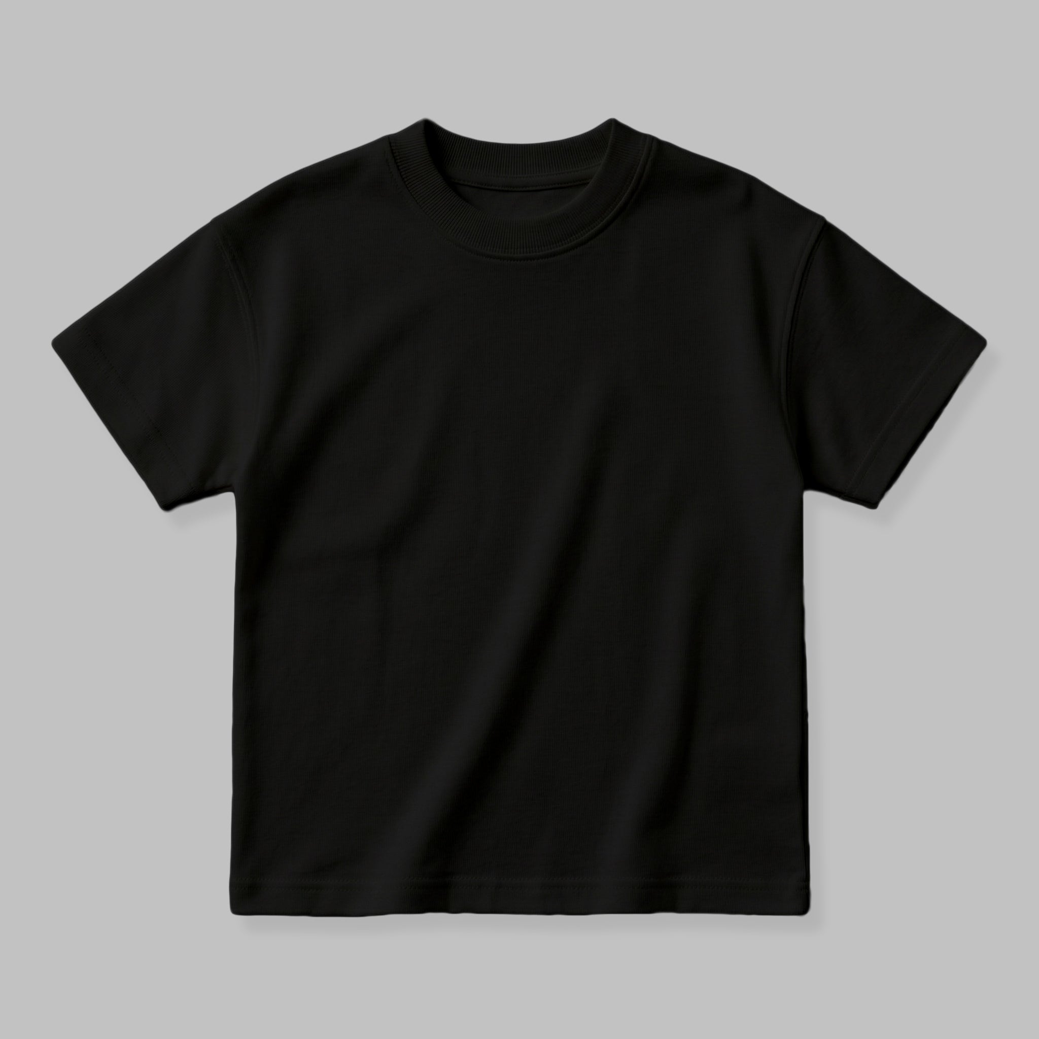 Çocuk giyim koleksiyonunuz için mükemmel bir temel oluşturan siyah renkli boş oversize tişört mockup görseli. Oeko-Tex standartlarına uygun %100 pamuklu heavyweight kumaşın tok ve kaliteli duruşunu detaylıca sergiler. Kalın dokusuna rağmen cilde nefes aldıran, terletmeyen ve yumuşacık bir yapıya sahiptir. 2-7 yaş çocukların rahatlığı için tasarlanmış geniş ribana yakasıyla kendi nakış veya baskı tasarımlarınızı hayal edebileceğiniz premium ve dayanıklı boş tişört modelidir.