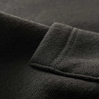 Siyah premium yetişkin pullover hoodie (kapüşonlu sweatshirt) modelinin kanguru cep yüzeyini ve tok pamuklu kumaş dokusunu gösteren makro detay çekimi. Ağır gramajlı (heavyweight) kumaşın yoğun örgüsü ve pürüzsüz yapısı ön plana çıkmaktadır. Kaliteli materyalin sunduğu dayanıklılık, şık döküm ve premium hissi vurgulayan yakın çekim.