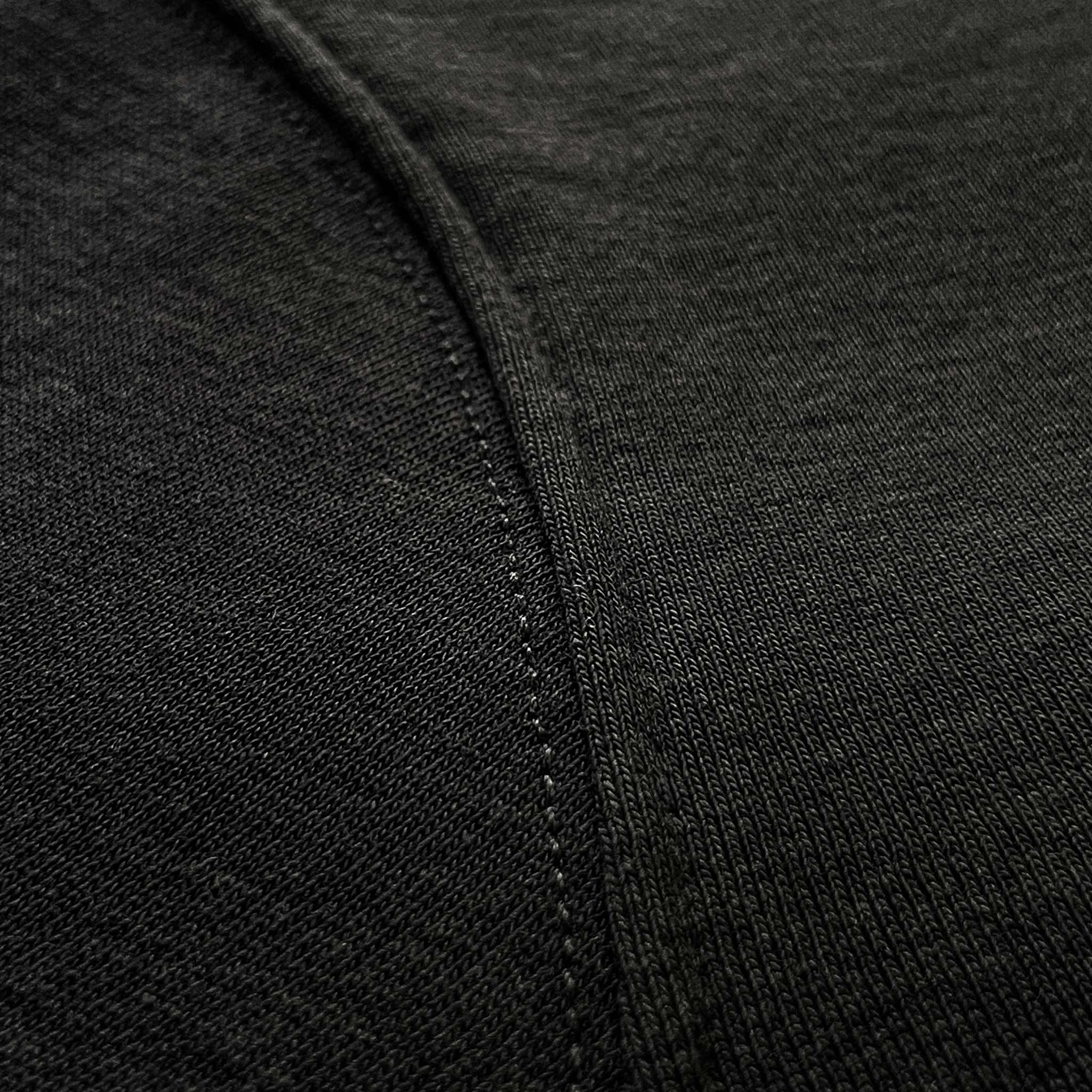 Siyah premium yetişkin hoodie (kapüşonlu sweatshirt) modelinin kol dikişi birleşimini ve tok pamuklu kumaş dokusunu gösteren makro detay çekimi. Ağır gramajlı (heavyweight) kumaşın yoğun örgüsü ve pürüzsüz yapısı üzerine uygulanmış sağlam, temiz dikiş işçiliği ön plana çıkmaktadır. Dayanıklılığı, premium hissi ve kusursuz yapım kalitesini vurgulayan yakın çekim.
