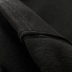 Yetişkinler için siyah premium hoodie (kapüşonlu sweatshirt) modelinin tok pamuklu kumaş dokusunu ve temiz dikişli kenar detayını gösteren yakın çekim. Kaliteli heavyweight jersey kumaşın pürüzsüz yapısı ve minimalist tasarımın kusursuz işçiliğini vurgulayan dikiş izi. Uzun ömürlü kullanım ve şık döküm sağlayan dokunun temel detayı.