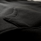 Siyah renkli premium çocuk hoodie modelinin kanguru cep birleşim yerindeki sağlam dikişlerini ve derin siyah kışlık kumaş dokusunu gösteren makro fotoğraf. Soğuk günlerde çocukların ellerini ısıtması için tasarlanmış geniş ve fonksiyonel cep. İçi şardonlu polar yapısıyla vücut sıcaklığını dengeleyen, nefes alan kumaşıyla gün boyu konfor sunan ve Oeko-Tex sertifikasıyla cilt dostu olduğunu kanıtlayan bu kapüşonlu sweatshirt, kusursuz işçiliğiyle her çocuğun kış gardırobunda bulunması gereken tasarımdır.
