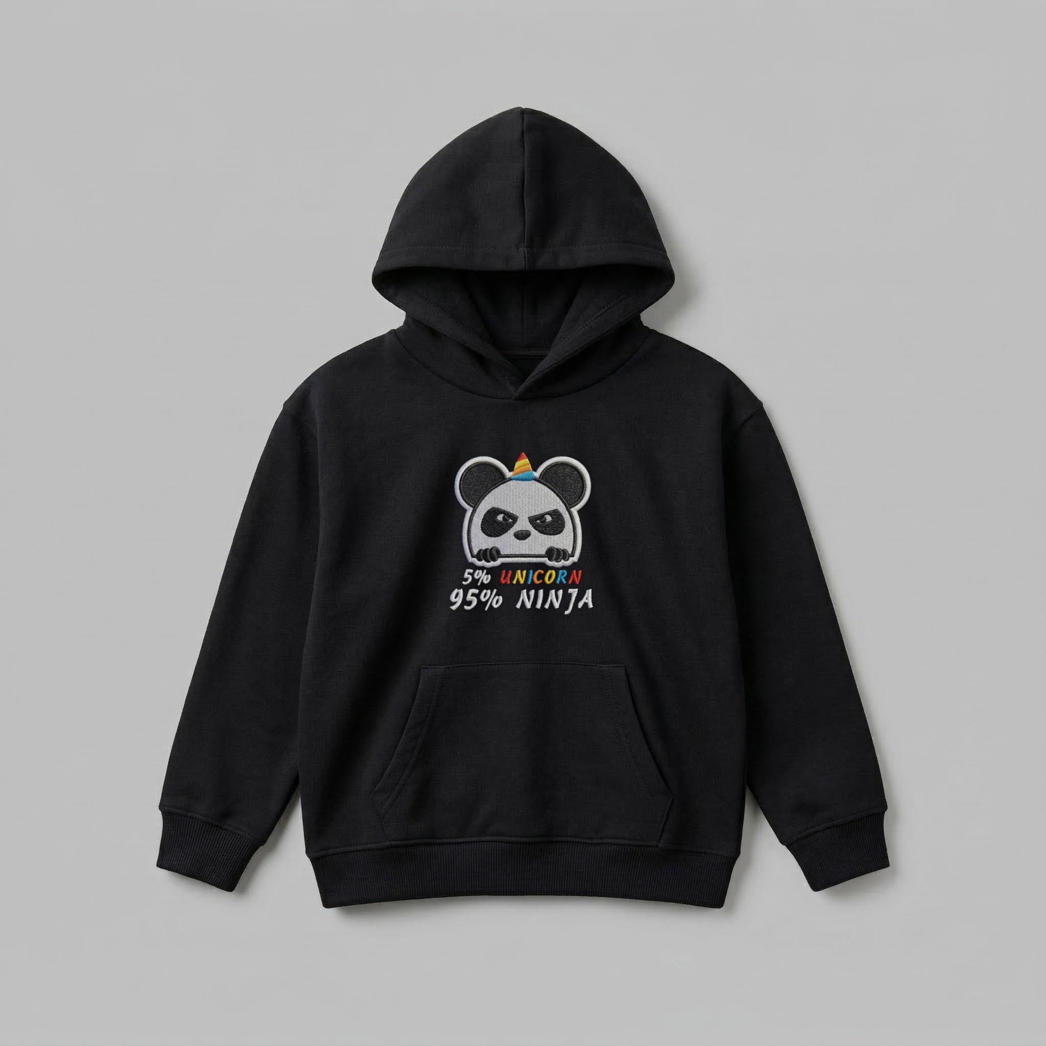 2-7 yaş grubu için üretilen siyah renkli çocuk kapüşonlu sweatshirt önden görünümü. Göğsünde komik '5% UNICORN, 95% NINJA' nakış tasarımı ve sevimli panda figürü yer alır. Oeko-Tex standartlarına uygun %65 pamuk içeriği ve şardonlu polar iç yüzeyi, soğuk havalarda rüzgarı keserek sıcacık tutar. Solmaya dirençli kumaşı, kanguru cebi ve esnek ribanalarıyla öne çıkan bu premium çocuk hoodie, terletmeyen sağlıklı yapısıyla aktif çocukların kışlık gardırobu için mükemmel bir rahatlıktır.