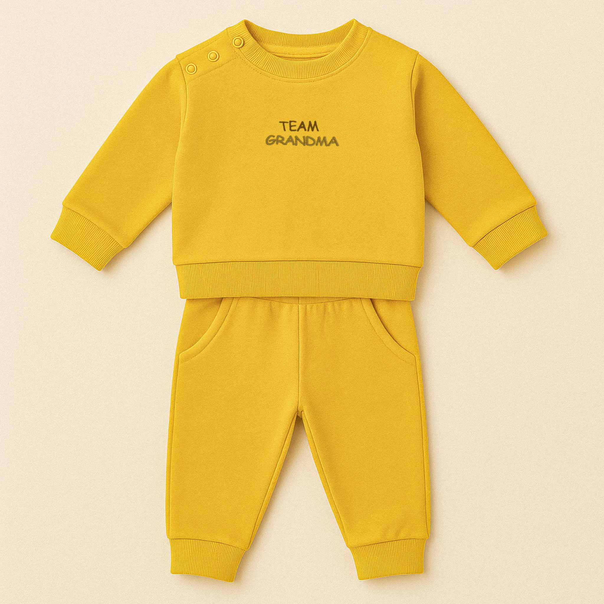 Hardal sarısı renkli, sweatshirt ve pantolondan oluşan "Team Grandma" nakışlı, omuzdan çıtçıtlı pamuklu bebek eşofman takımı.