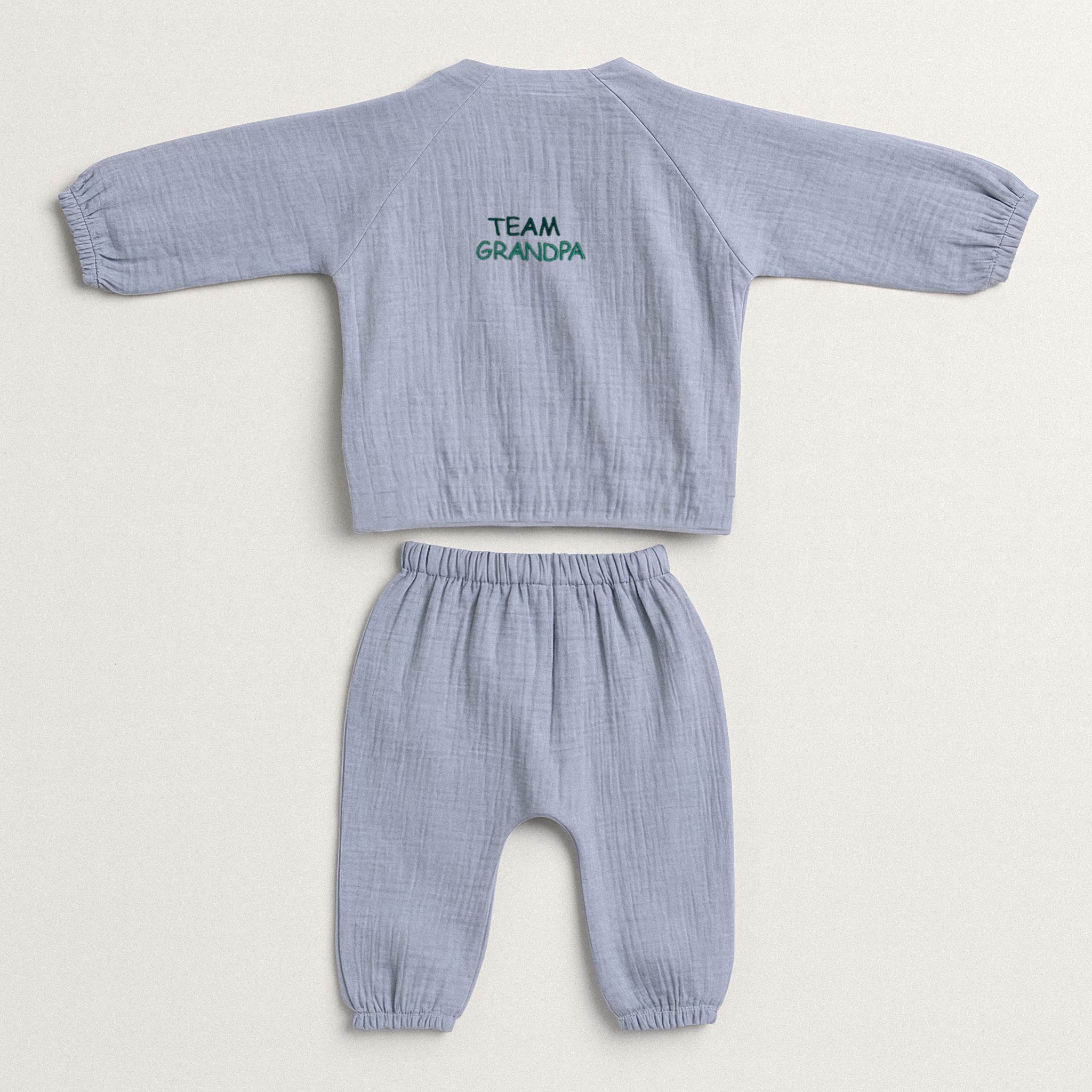 İndigo mavisi renginde, müslin kumaştan yapılmış, üzerinde 'Team Grandpa' nakışı bulunan, yandan bağlamalı kimono üst ve pantolondan oluşan yenidoğan bebek takımı.