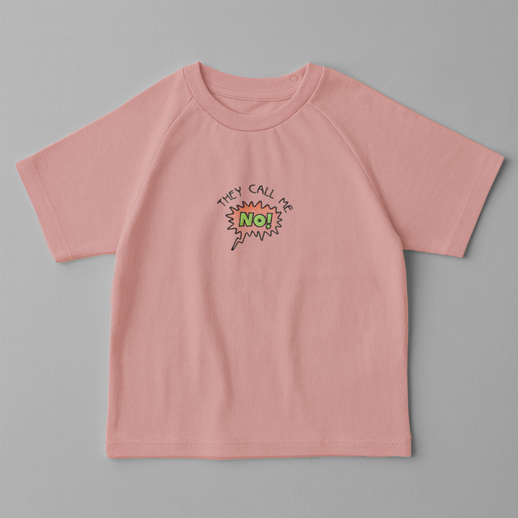 Gül kurusu (pembe) renkli, reglan kollu, omuzdan çıtçıtlı bebek tişörtü. Göğüs kısmında çizgi roman stilinde "THEY CALL ME NO!" nakışı bulunmaktadır.