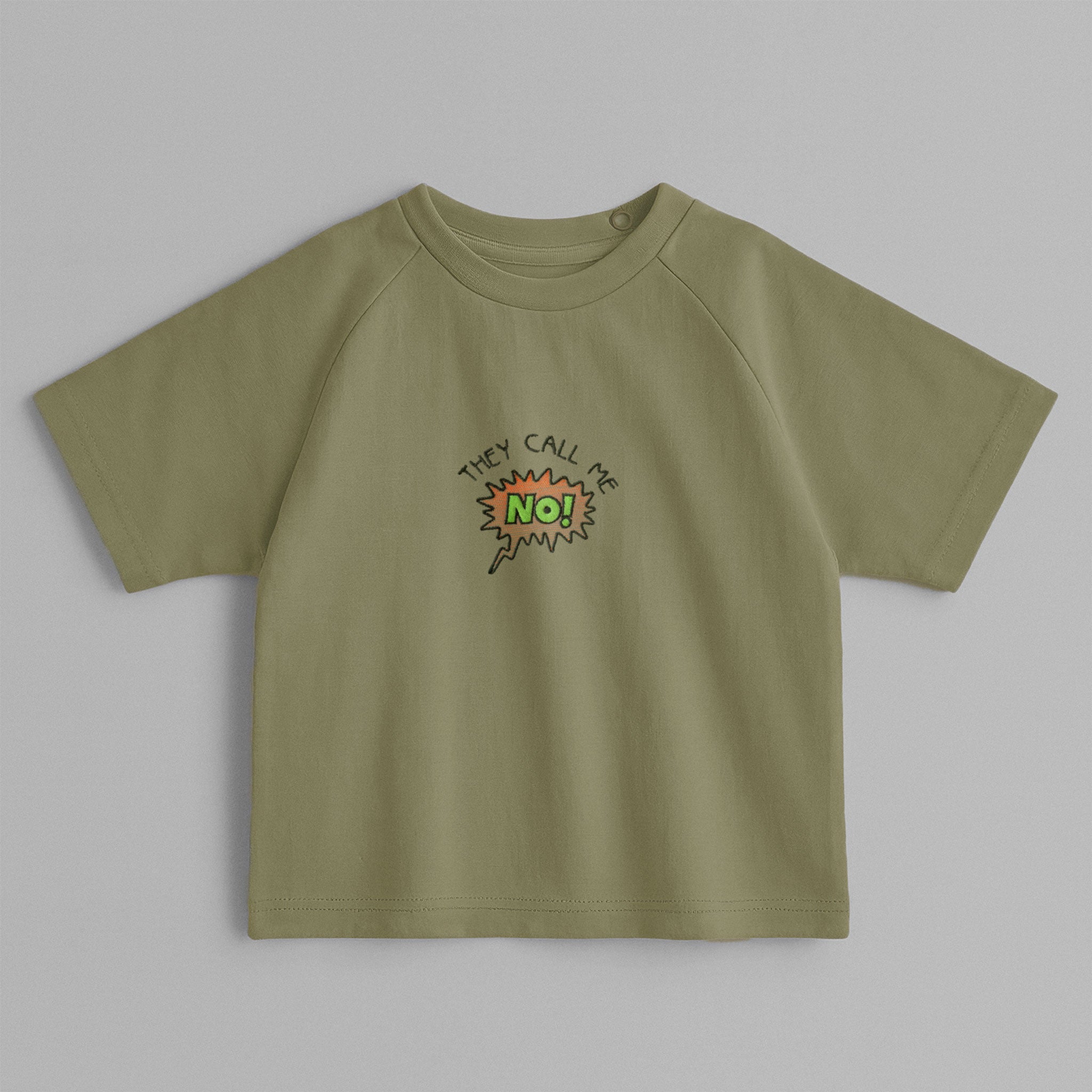 Haki yeşili, reglan kollu, omuzdan çıtçıtlı bebek tişörtü. Göğüs kısmında çizgi roman stilinde "THEY CALL ME NO!" nakışı bulunmaktadır.