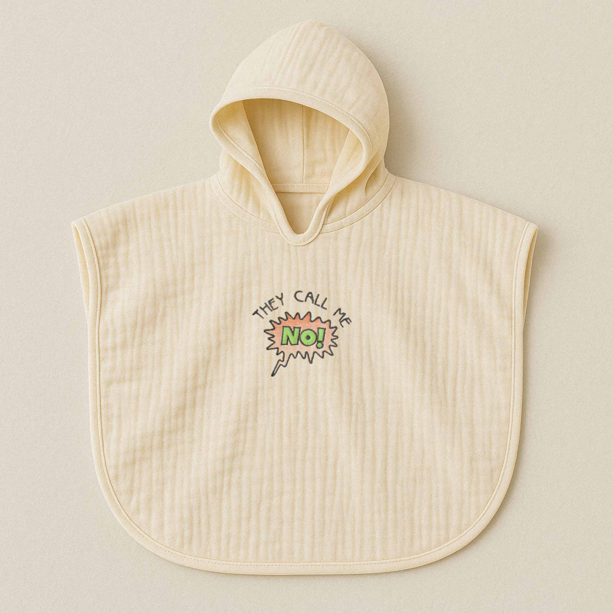 Ekru (doğal bej) renginde, kapüşonlu, müslin kumaştan bebek ve çocuk pançosu. Göğüs kısmında çizgi roman stilinde "THEY CALL ME NO!" yazısı işlenmiştir.