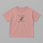 Gül kurusu (pembe) renkli, oversize kesim, üzerinde sevimli dinozor nakışı ve 'Tiny Arms Big Dreams' yazısı bulunan pamuklu çocuk tişörtü.