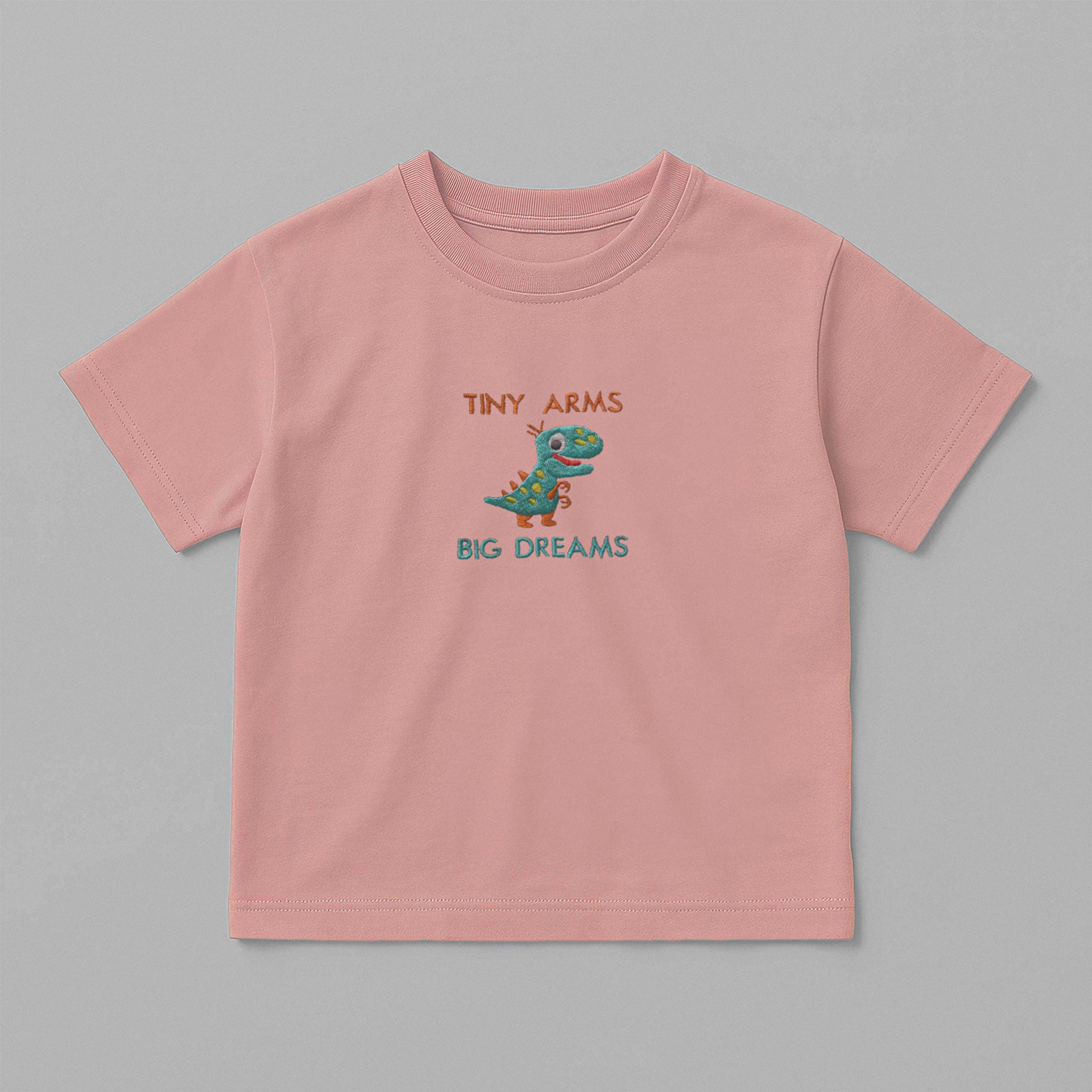 Gül kurusu (pembe) renkli, oversize kesim, üzerinde sevimli dinozor nakışı ve 'Tiny Arms Big Dreams' yazısı bulunan pamuklu çocuk tişörtü.
