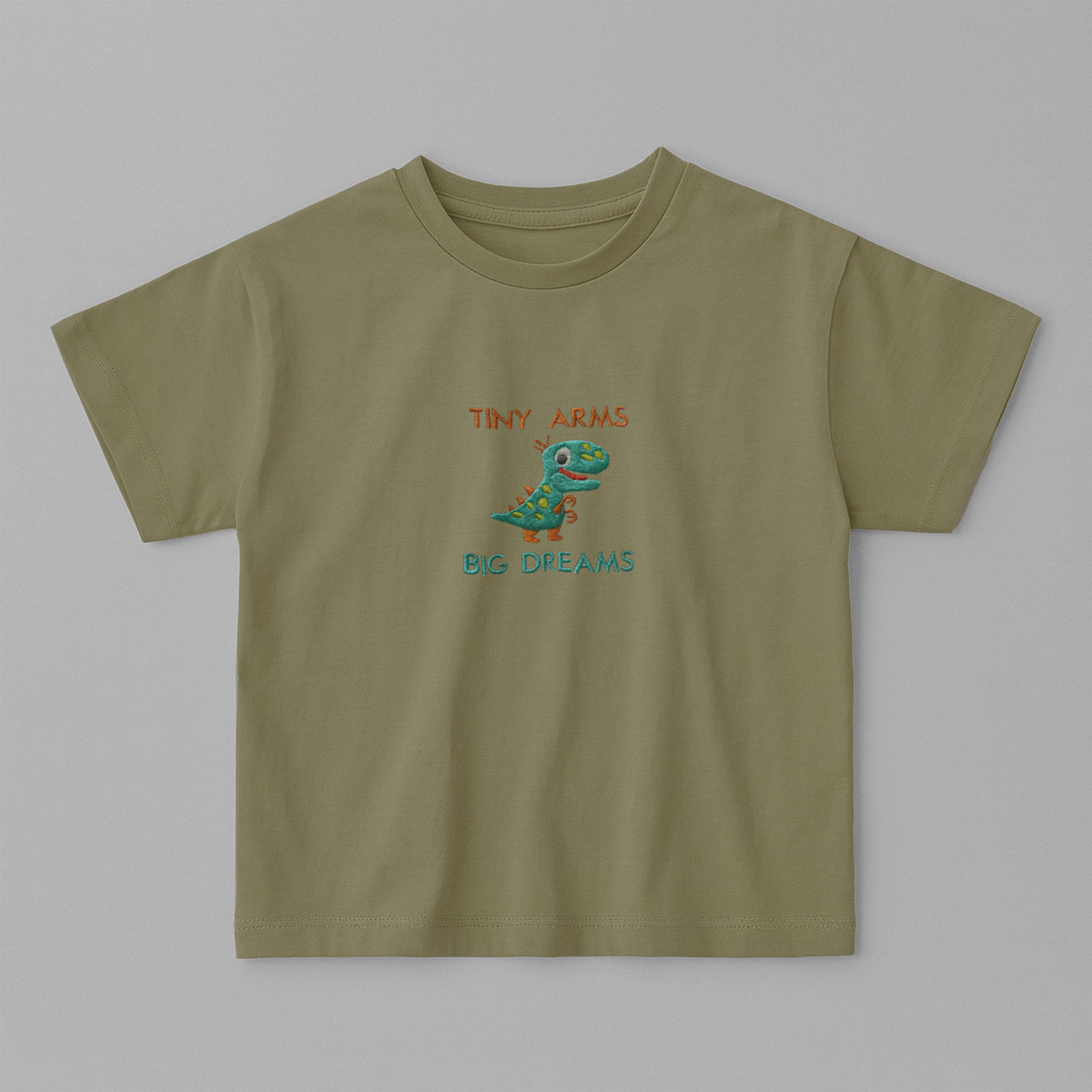 Haki yeşili, oversize kesim, üzerinde sevimli dinozor nakışı ve 'Tiny Arms Big Dreams' yazısı bulunan pamuklu çocuk tişörtü.