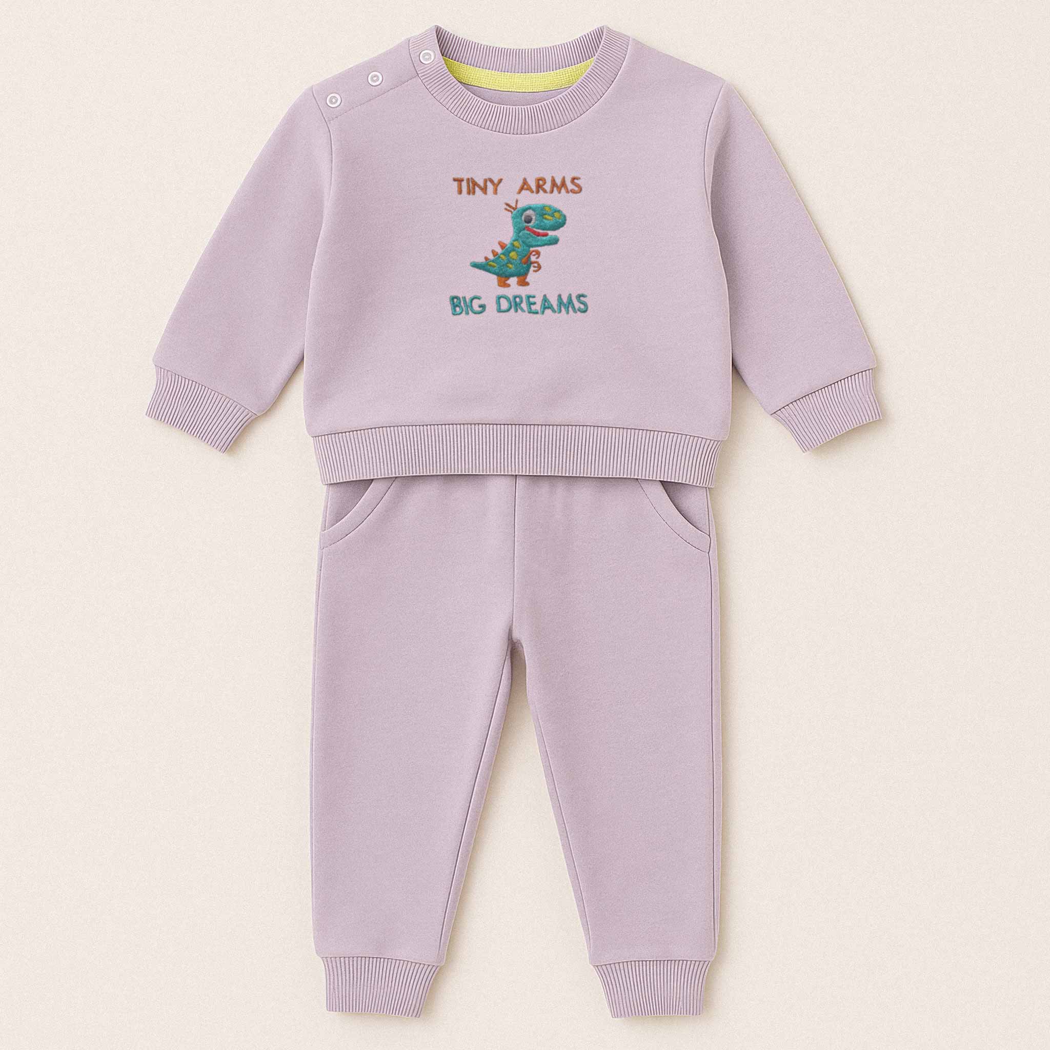 Lila (leylak) renkli, sweatshirt ve pantolondan oluşan, üzerinde sevimli bir T-Rex dinozoru ve "Tiny Arms Big Dreams" baskısı bulunan, omuzdan çıtçıtlı pamuklu bebek eşofman takımı.