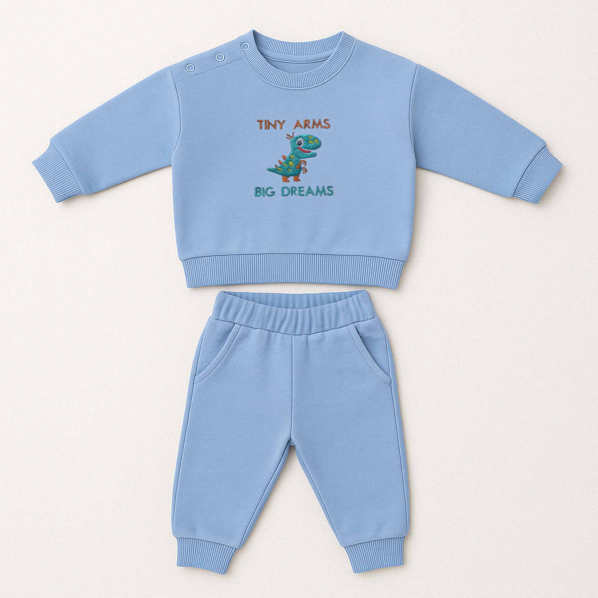 Mavi renkli, sweatshirt ve pantolondan oluşan, üzerinde sevimli bir T-Rex dinozoru ve "Tiny Arms Big Dreams" baskısı bulunan, omuzdan çıtçıtlı pamuklu bebek eşofman takımı.