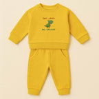 Hardal sarısı renkli, sweatshirt ve pantolondan oluşan, üzerinde sevimli bir T-Rex dinozoru ve "Tiny Arms Big Dreams" baskısı bulunan, omuzdan çıtçıtlı pamuklu bebek eşofman takımı.