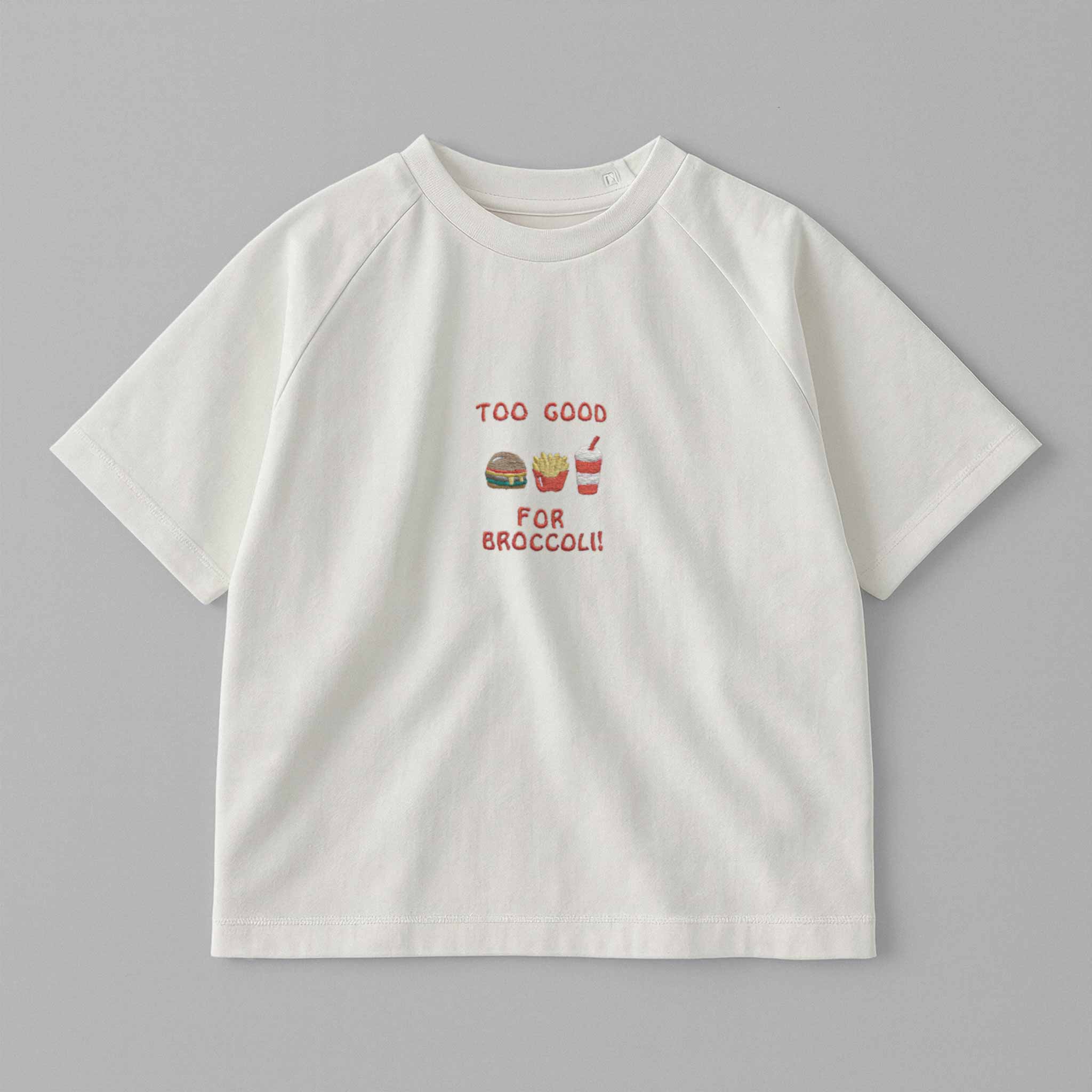 Ekru renkli, reglan kollu, omuzdan çıtçıtlı bebek tişörtü. Göğüs kısmında "Too Good for Broccoli" yazısı ve hamburger, patates, içecek nakışları bulunmaktadır.