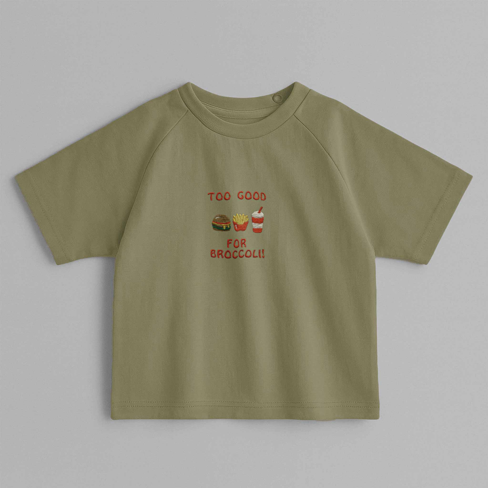 Haki yeşili, reglan kollu, omuzdan çıtçıtlı bebek tişörtü. Göğüs kısmında "Too Good for Broccoli" yazısı ve hamburger, patates, içecek nakışları bulunmaktadır.