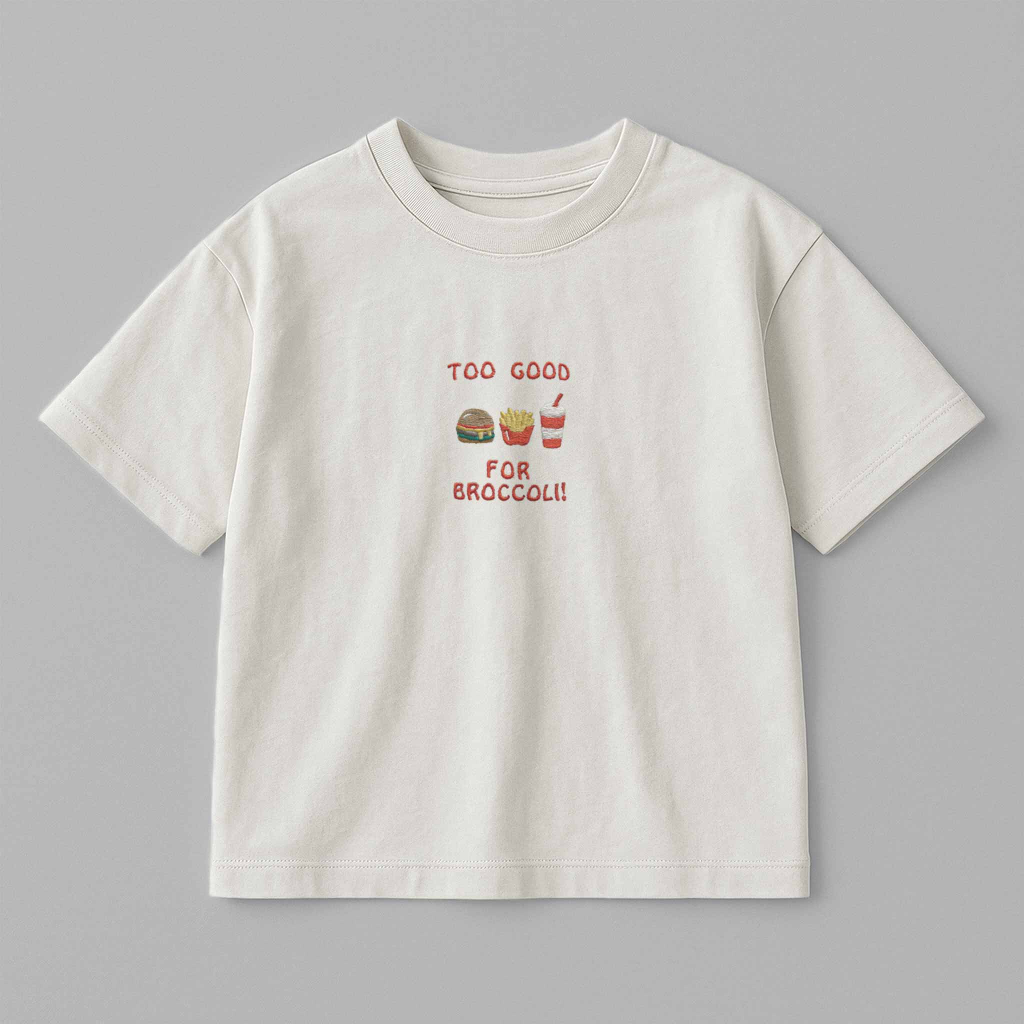 Ekru renkli, oversize kesim, 1-5 yaş için pamuklu çocuk tişörtü. Göğüs kısmında "Too Good for Broccoli" yazısı ve hamburger, patates, içecek nakışları bulunmaktadır.