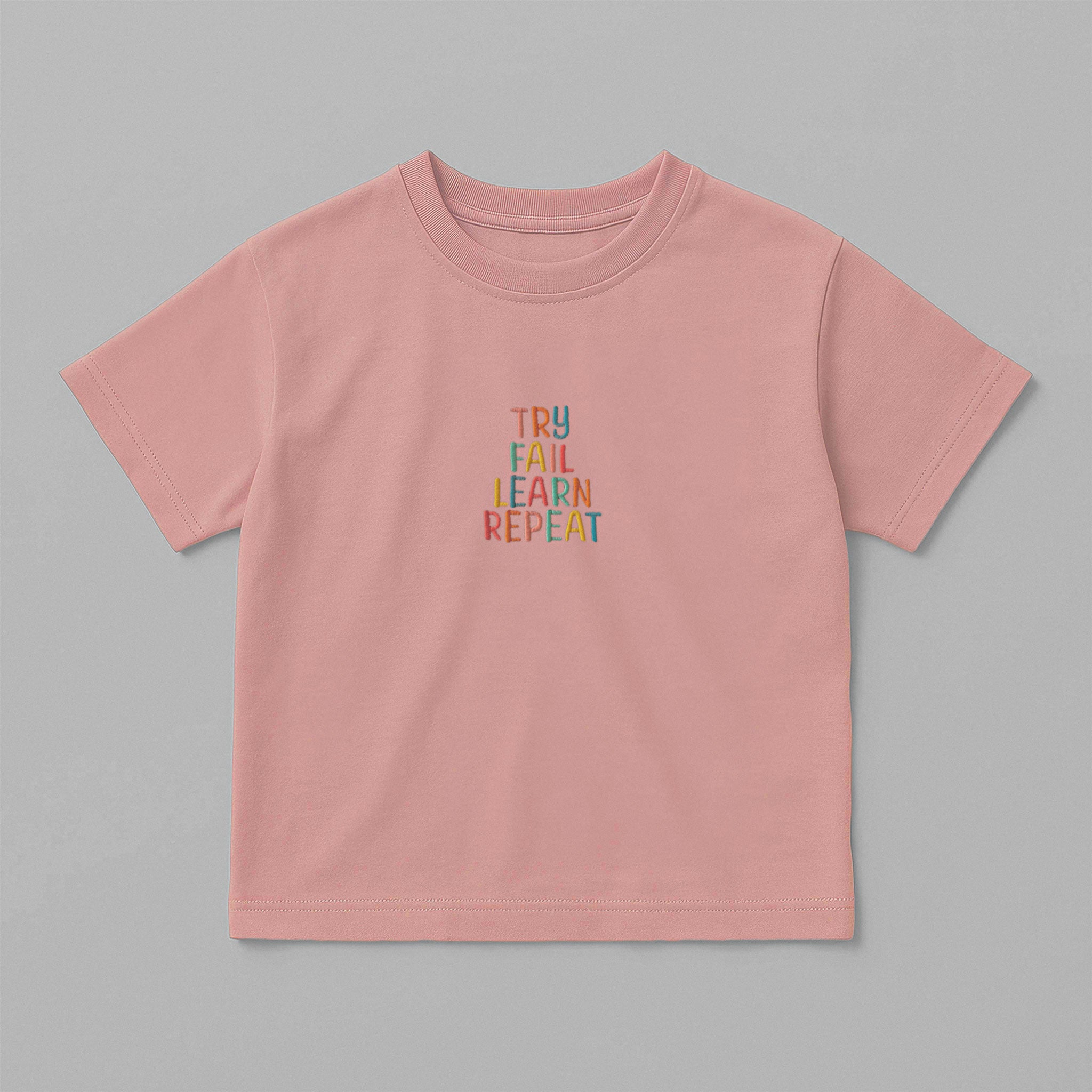 Gül kurusu (pembe) renkli, oversize kesim, 1-5 yaş için pamuklu çocuk tişörtü. Göğüs kısmında renkli ipliklerle "TRY FAIL LEARN REPEAT" yazısı işlenmiştir.