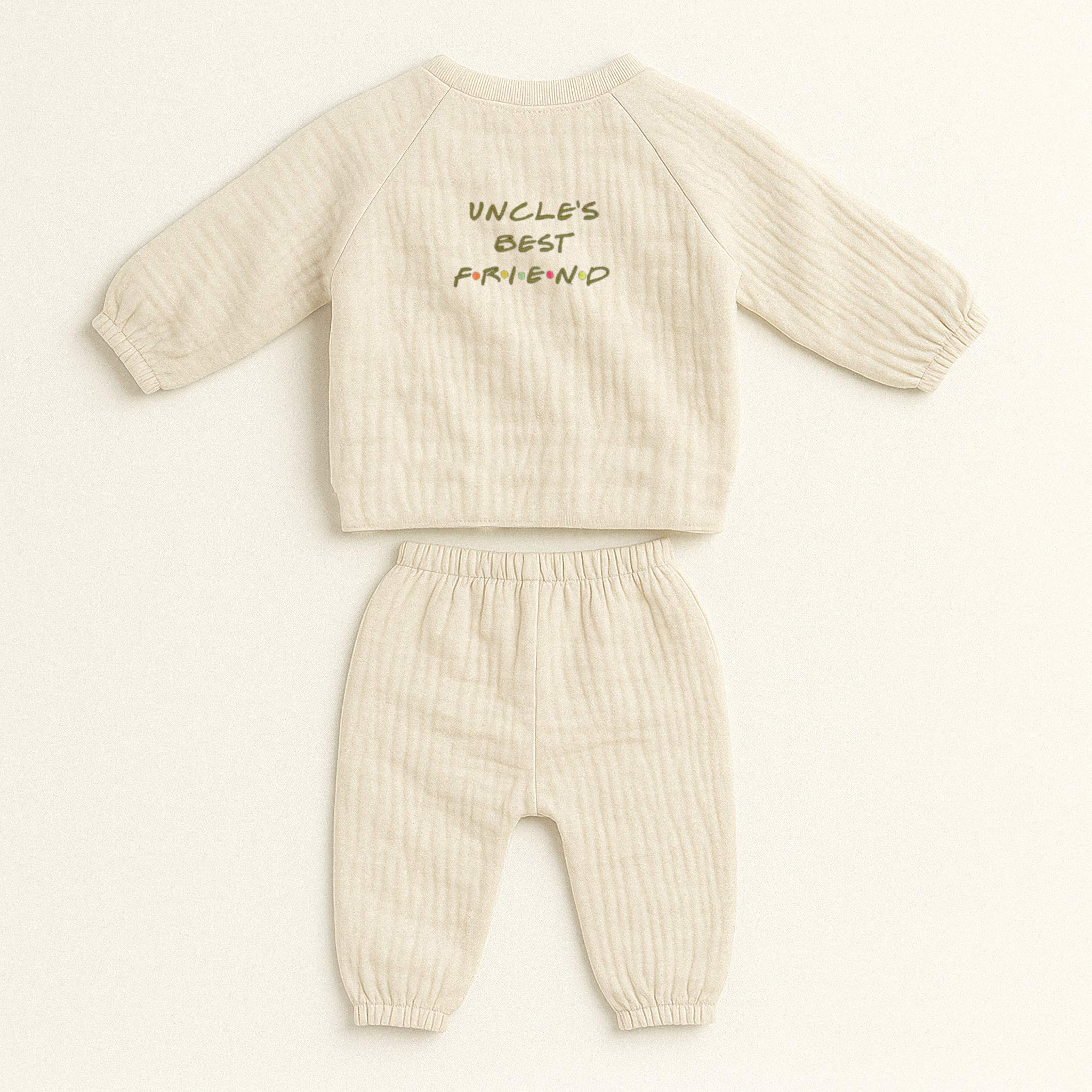 Doğal bej (ekru) renginde, müslin kumaştan yapılmış, üzerinde "Uncle's Best Friend" baskısı bulunan, yandan bağlamalı kimono üst ve pantolondan oluşan yenidoğan bebek takımı.