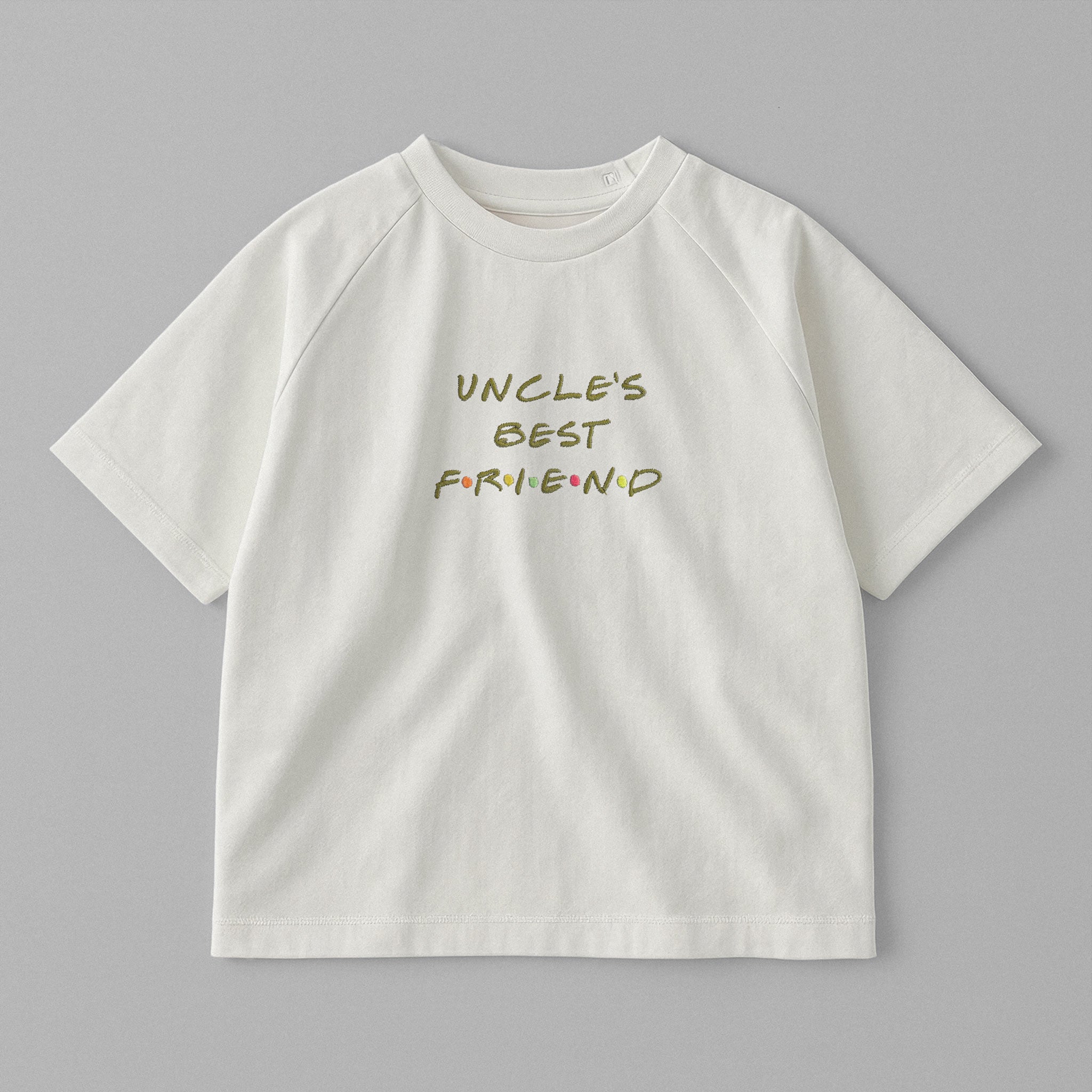 Ekru renkli, omuzdan çıtçıtlı, üzerinde Friends dizisi fontuyla ve renkli detaylarla 'UNCLE'S BEST FRIEND' nakışı bulunan oversize pamuklu bebek tişörtü.