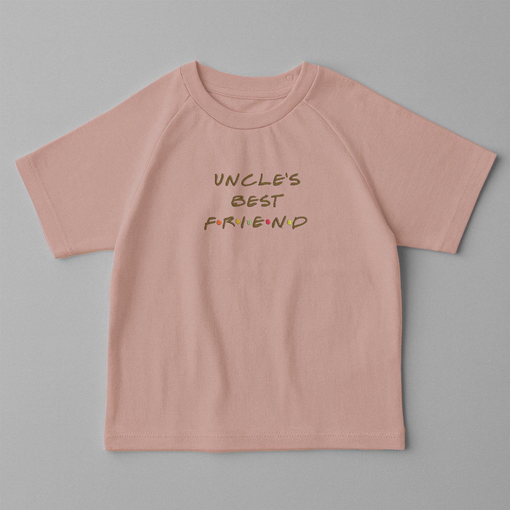 Gül kurusu (pembe) renkli, omuzdan çıtçıtlı, üzerinde Friends dizisi stiliyle 'UNCLE'S BEST FRIEND' nakışı bulunan oversize pamuklu bebek tişörtü.