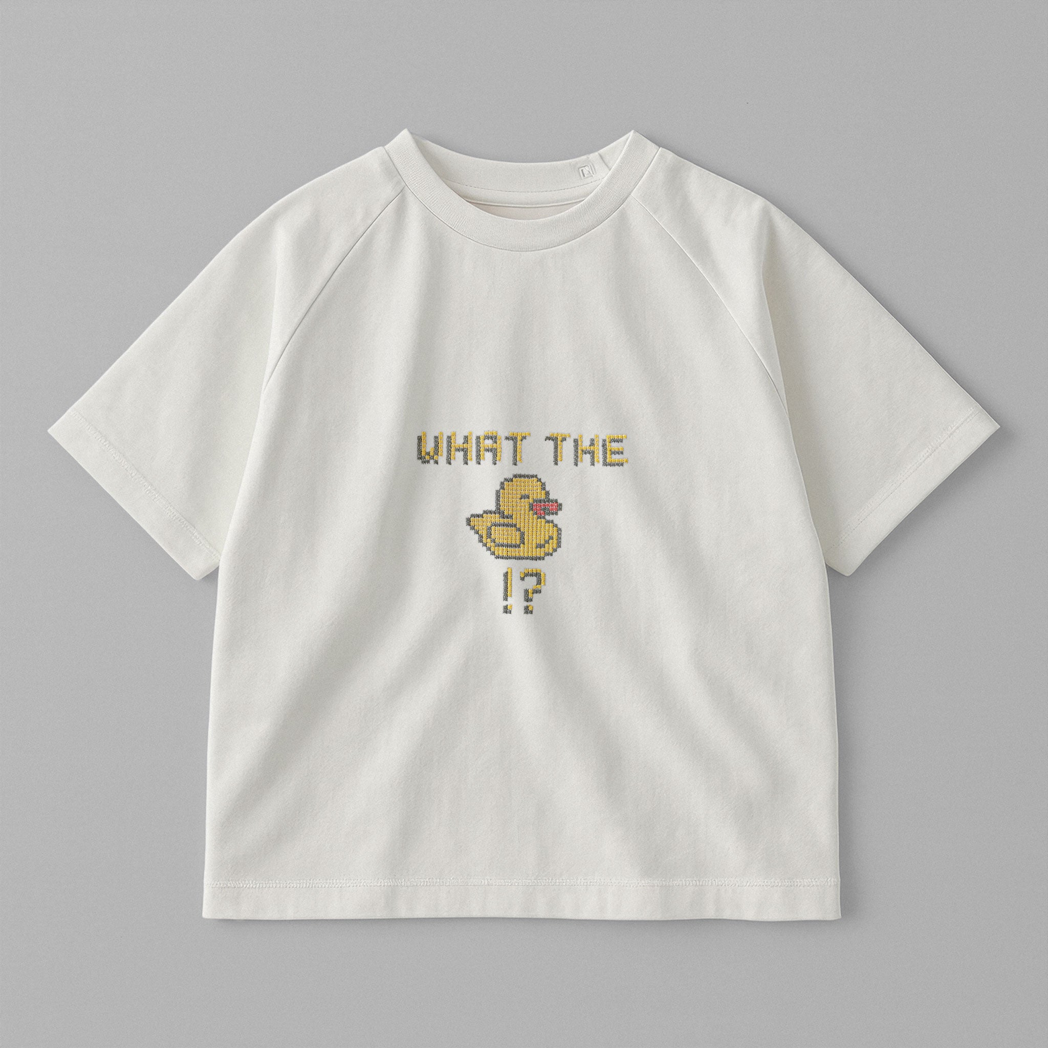 Ekru renkli, reglan kollu, omuzdan çıtçıtlı bebek tişörtü. Göğüs kısmında piksel tasarımlı "What the duck" ve ördek figürü nakışı bulunmaktadır.