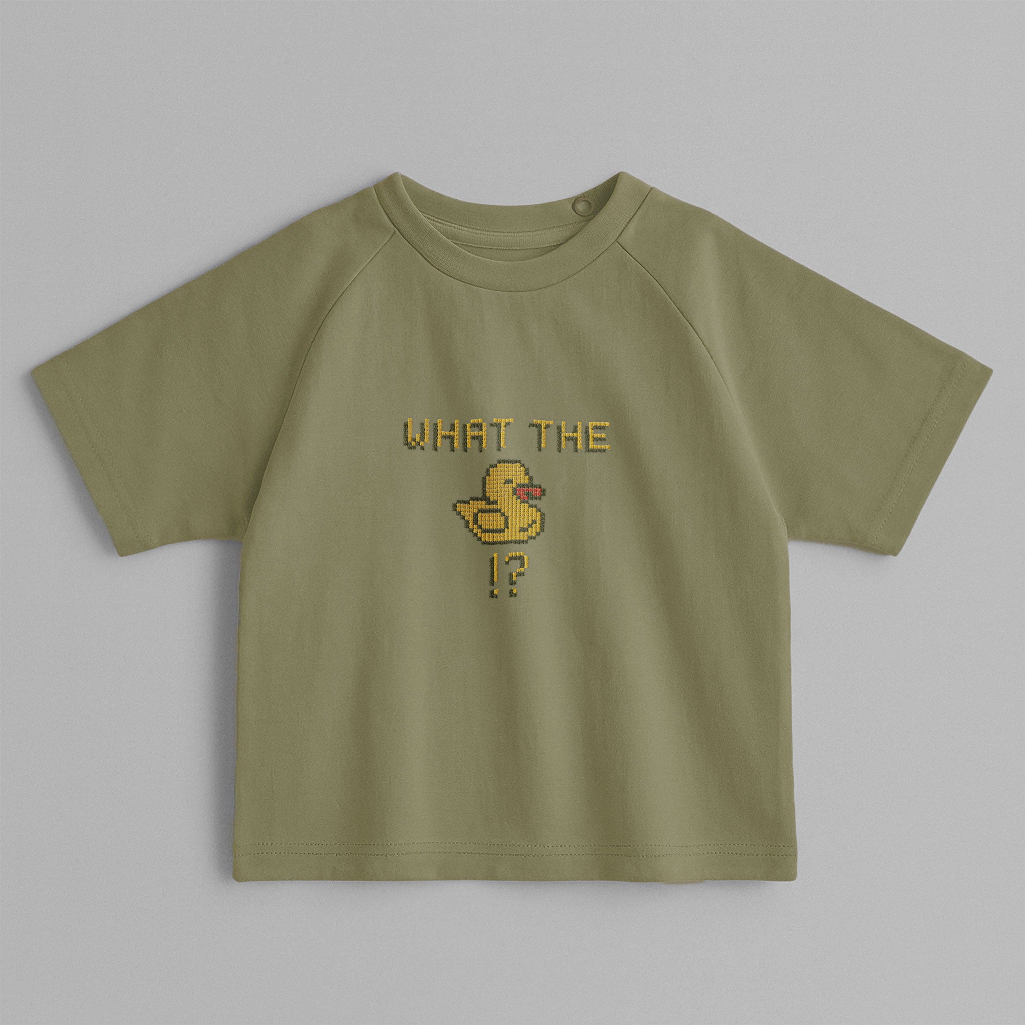 Haki yeşili, reglan kollu, omuzdan çıtçıtlı bebek tişörtü. Göğüs kısmında piksel tasarımlı "What the duck" ve ördek figürü nakışı bulunmaktadır.