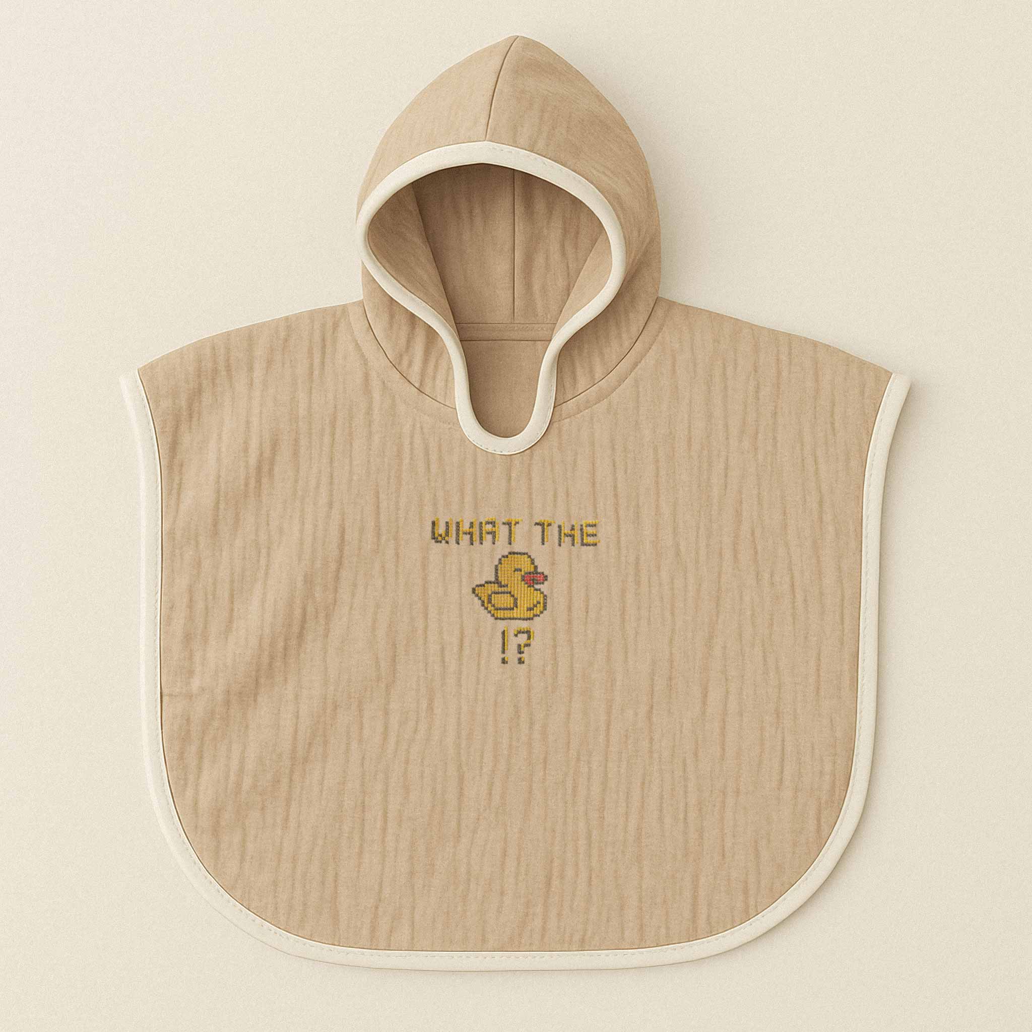 Somon rengi (bej), kapüşonlu, müslin kumaştan bebek ve çocuk pançosu. Göğüs kısmında "WHAT THE" yazısı, bir ördek figürü ve soru işareti nakışla işlenmiştir.