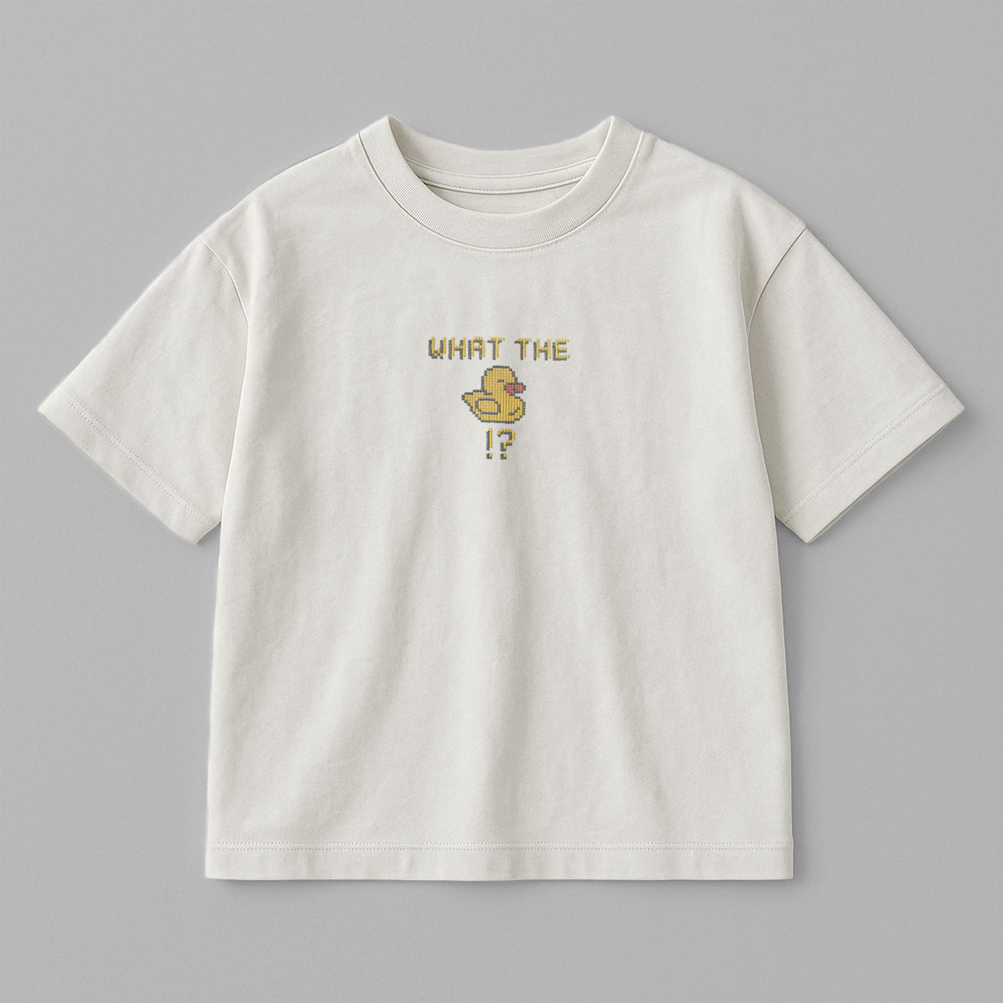 Ekru renkli, oversize kesim, 1-5 yaş için pamuklu çocuk tişörtü. Göğüs kısmında piksel tasarımlı "What the duck" ve ördek figürü nakışı bulunmaktadır.
