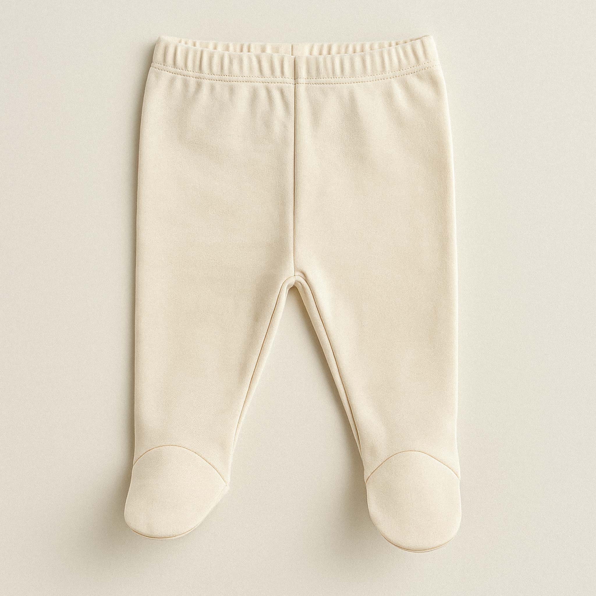 Ekru renkli, %100 pamuklu, beli lastikli, kendinden patikli yenidoğan bebek pantolonu.